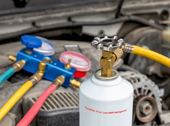 Automobile air conditioner freon can and test gauges under hood of car.